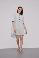 Vestido corto tipo túnica color celeste, de lino, con cuello camisero, mangas cortas y cierre frontal con botones de madera.