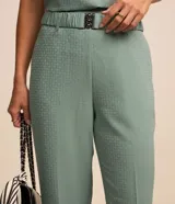 Pantalón de corte recto para mujer, confeccionado en jacquard negro con textura. Cuenta con cintura elástica integrada, hebilla decorativa frontal y cierre lateral.