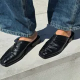 Zueco de cuero color marrón con diseño fruncido en la parte delantera y taco bajo.