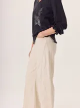 Pantalon de corte ancho y holgado, confeccionado en una mezcla de algodón, viscosa y lino. Presenta un diseño de tiro medio con bolsillos traseros y costuras visibles que recorren el largo de las piernas.