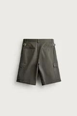 Bermuda cargo color verde militar de corte relaxed fit, confeccionada en tejido de algodón. Cuenta con bolsillos laterales con solapa en las perneras, trabillas en la cintura con ajuste lateral y cierre frontal con cremallera y botón.
