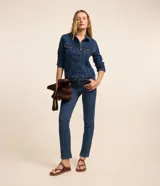 Pantalón slim de jean azul, tiro medio, con bolsillos, trabillas para cinto y pequeña abertura en el bajo. Cuenta con cierre frontal de botón y cremallera.