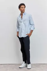 Camisa de corte regular, color celeste con rayas verticales blancas muy finas, cuello clásico y mangas largas con puños abotonados.