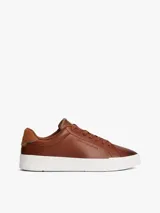 Zapatillas de estilo tenis Tommy Hilfiger confeccionadas en piel color marrón, con diseño de corte bajo, cordones al tono y suela de goma blanca. Presenta un panel de gamuza a contraste en el talón y el logo de la marca grabado en el lateral.