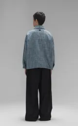 Campera de denim rígido con textura de trama única, corte oversize, cuello camisero, cierre frontal con botones y bolsillos delanteros con solapa.