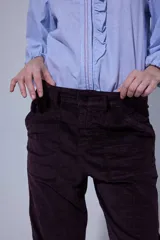 Pantalón de corte recto y tiro medio, confeccionado en tejido con patrón de cuadros oscuros. Presenta bolsillos frontales amplios y terminación con dobladillo en los tobillos.