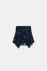 Falda corta de tiro medio confeccionada en tejido tipo tul color azul marino. Presenta un diseño con drapeado lateral en la cintura, bordados florales con aplicación de abalorios y bajo asimétrico.
