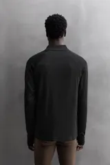 Sudadera negra de tejido técnico Polartec© con interior en estructura waffle. Tiene cuello alto con cremallera, mangas largas con puños ajustables con abertura para el pulgar y logo Polartec© bordado en el hombro.