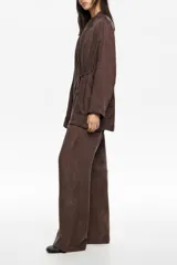 Chaqueta de corte cruzado color marrón, con cuello de solapa, cierre mediante lazo en la cintura y bolsillos de plastrón frontales.