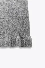Jersey de punto de cuello redondo y manga corta, con detalle de volantes en el ruedo y en los puños.