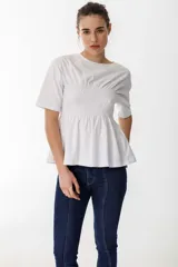 Remera blanca de algodón con cuello redondo, mangas cortas y detalle de fruncido tipo nido de abeja en la zona del busto, creando un efecto peplum.