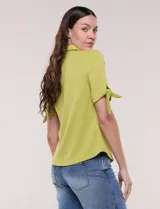 Camisa blanca de manga corta con cuello solapa, cierre frontal de botones, detalles bordados al tono en el pecho y lazos para anudar en las mangas.