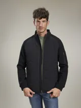 Campera negra con cuerpo acolchado con diseño de ondas y mangas de tejido de punto. Cuenta con cierre frontal, cuello alto, bolsillos laterales y bolsillo con cierre en la manga izquierda.