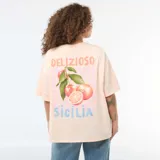 Remera oversize de manga corta color salmón con estampado frontal que incluye texto y gráfico de naranjas.