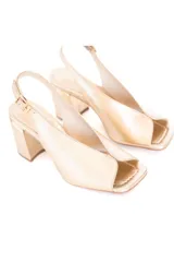 Zapato tipo sandalia con talón descubierto y puntera abierta, confeccionado en cuero natural color dorado. Presenta un diseño con escote en el empeine, cierre con hebilla lateral y taco cuadrado de altura media.