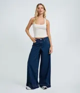 Pantalón de jean azul oscuro con corte super wide leg, cintura media, bolsillos funcionales y ruedo deshilachado.