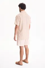 Camisa de manga corta con diseño a rayas verticales en tonos beige y marrón.