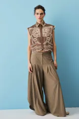 Pantalón marrón de corte ancho y fluido, con pinzas frontales y tiro alto.