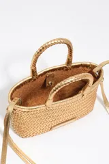 Minibolso trenzado Bimba y Lola de color dorado metalizado, confeccionado en piel vacuna. Posee asas de mano rígidas y correa ajustable para hombro, con etiqueta frontal de piel con el logo de la marca.