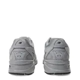 Championes New Balance modelo 509, color gris claro con detalles en gris oscuro y negro. Presentan una combinación de malla transpirable y superposiciones de gamuza. El logo 'N' lateral es negro.