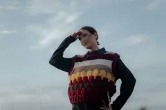 Chaleco tejido de punto con diseño de rayas horizontales y bloques de color en tonos bordó, beige, blanco y amarillo. Presenta cuello redondo y terminaciones acanaladas.