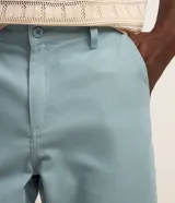 Bermuda básica en sarga de algodón color salmón, de corte recto con trabillas en la cintura, cierre de botón y cremallera, y bolsillos.