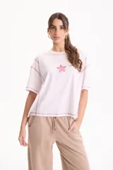 Remera de algodón blanca de manga corta y corte semi boxy, con costuras a contratono en color rosado, detalles de cortes y bordado de estrella de mar en el frente.