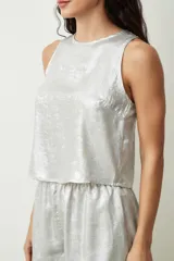 Blusa plateada sin mangas con textura brillante.