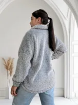 Campera gris de tela tipo peluche con cierre frontal y bolsillo de cuero sintético en el pecho.