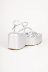 Sandalias de plataforma color blanco con tiras trenzadas y pulsera al tobillo.