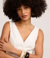 Chaleco femenino color blanco, sin mangas, con escote en V y abotonadura frontal. Presenta pences para un calce entallado y espalda descotada.