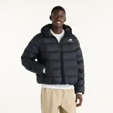 Campera puffer New Balance modelo Boston, color negro, con capucha, cierre frontal completo y bolsillos laterales. Presenta el logo de la marca bordado en blanco en el pecho.