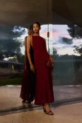 Vestido largo bordó con brillos, escote halter y diseño fluido de corte acampanado.