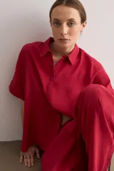 Camisa de manga corta color rojo, de corte holgado, con cuello camisero clásico y cierre frontal abotonado.
