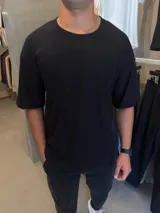Remera de corte oversize color negro, con cuello redondo y mangas cortas.
