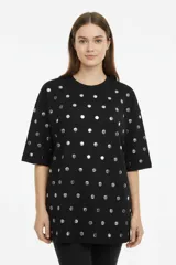 Remera de algodón negra, de corte holgado y manga corta, con cuello redondo a la base y diseño de tachas metálicas plateadas en formato lunares distribuidas por toda la prenda.