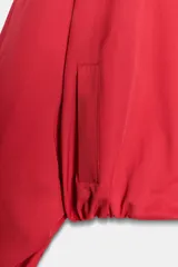 Chaqueta tipo bomber de Zara, color rojo, con escote en pico, cierre frontal cruzado con botones a presión y mangas largas abullonadas con puños elásticos. Cuenta con bolsillos delanteros y forro interior a tono.