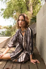 Vestido camisero con cuello a la base y mangas al codo, con botones al frente y estampado tie dye en tonos grises y blancos.