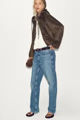 Chaqueta bomber de efecto ante en color marrón, con capucha ajustable mediante cordones, cierre frontal con cremallera, bolsillos laterales y bajo con elástico interior.