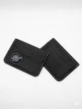 Tarjetero de cuero negro con textura granulada, cuenta con múltiples ranuras para tarjetas y un aplique circular con logo bordado en el frente.
