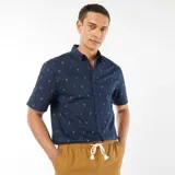 Camisa azul marino de corte recto y manga corta, con estampado de palmeras blancas.