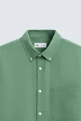 Camisa celeste a rayas verticales, de corte relaxed fit, confeccionada en lino y algodón. Tiene cuello abotonado, manga larga con puños abotonados, bolsillo de parche en el pecho y cierre frontal con botones.