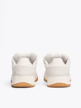 Zapatillas Tommy Jeans de corte bajo, color gris claro, confeccionadas en ante con interior de poliéster y suela de goma color caramelo. Presentan cordones blancos, logo de la marca en la lengüeta y etiqueta de Tommy Jeans en el lateral.