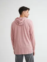 Remera manga larga color beige con capucha y media cartera de botones. Presenta bolsillo tipo canguro y rayas horizontales en el pecho en color marrón.