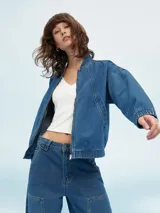 Campera bomber de denim azul con cierre frontal, bolsillos laterales y elástico en puños y cintura.