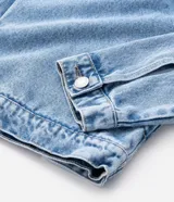 Campera de jean en color azul con efecto desgastado, cuello clásico, cierre frontal con botones metálicos y dos bolsillos con solapa en el pecho.