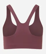 Top deportivo de microfibra color ciruela, con escote cuadrado frontal y espalda tipo nadador. Presenta un pequeño logo bordado en blanco en el centro del pecho.