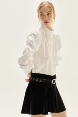 Falda corta de terciopelo negro con diseño ajustado en la cadera y volado en el ruedo.