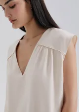 Blusa naranja sin mangas con escote en V y detalle de frunces en los hombros.