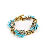 Pulsera dorada con eslabones gruesos, adornada con piedras brillantes y detalles turquesa.